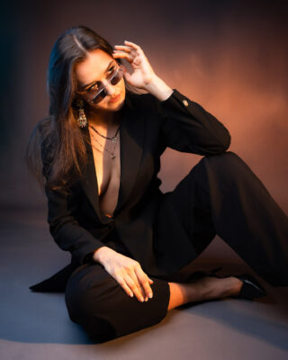 Sesja kobieca Wrocław, portret w czarnym garniturze i okularach przeciwsłonecznych, studyjne światło