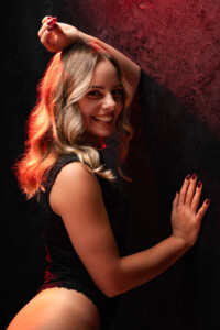 Sesja buduarowa Wrocław, uśmiechnięty portret w czarnej bieliźnie, czerwone światło i faktura tła